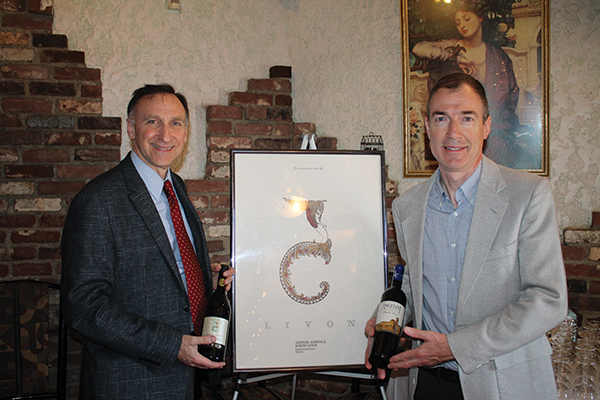 Julius Angelini, Owner, Angelini Wine with Paul Cullen, CT Sales Manager, Angelini Wine, standing beside framed artwork of an art deco Livon Wine label.